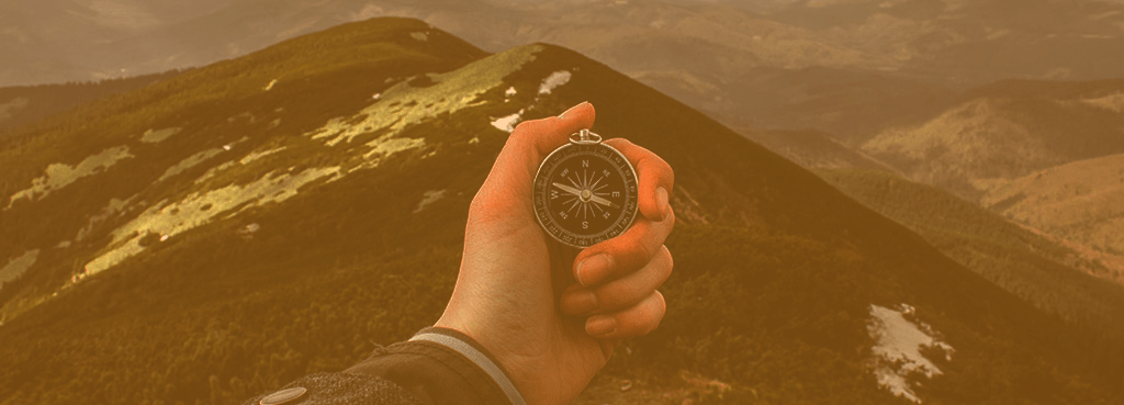 Hand holding a compass yellow tint. Portfolio modernization article by Charlie Feld.